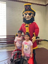 Captain Vic and two children holding new backpacks