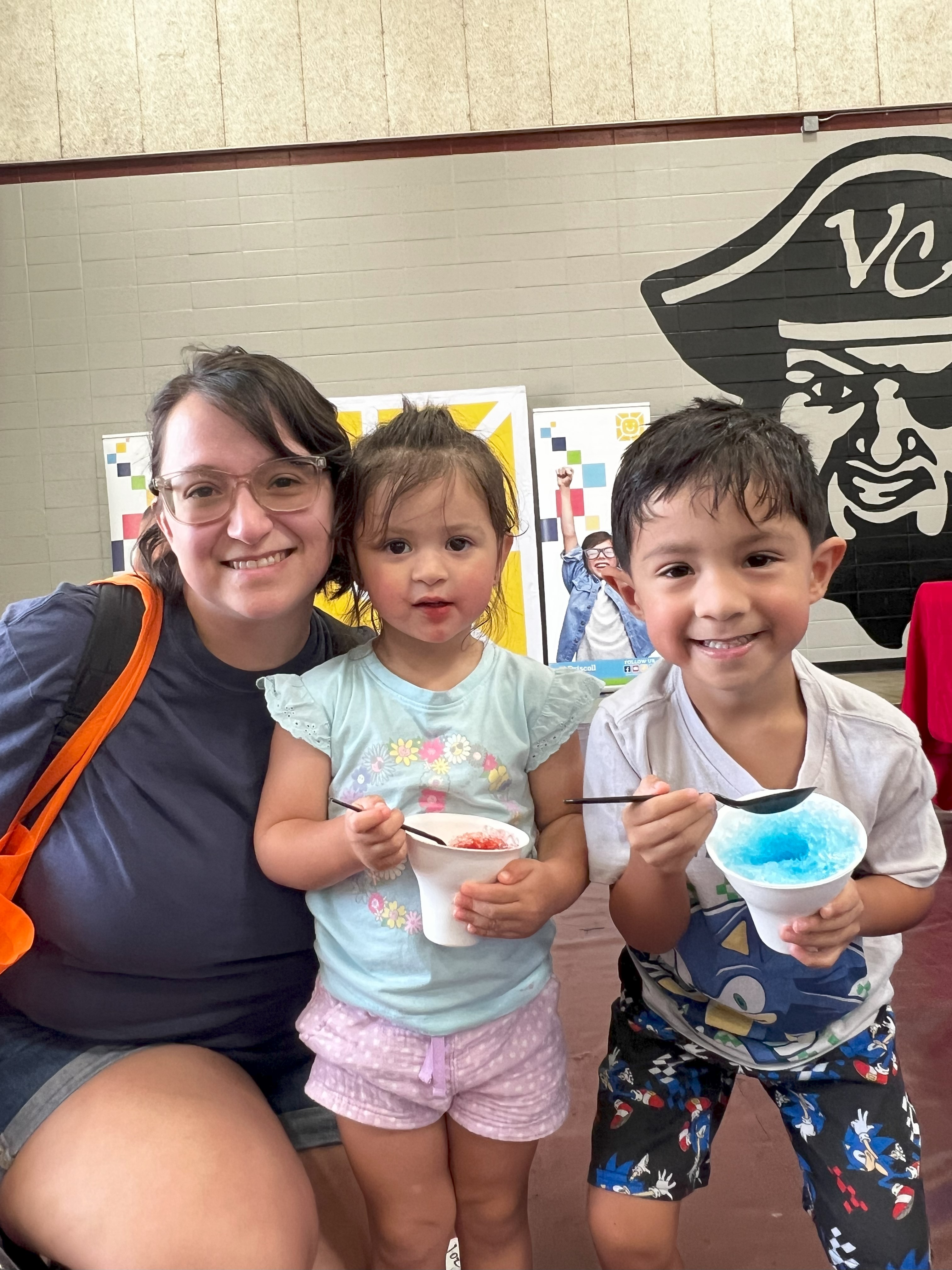 A mom and her two kids enjoy snow cones at the resource fair