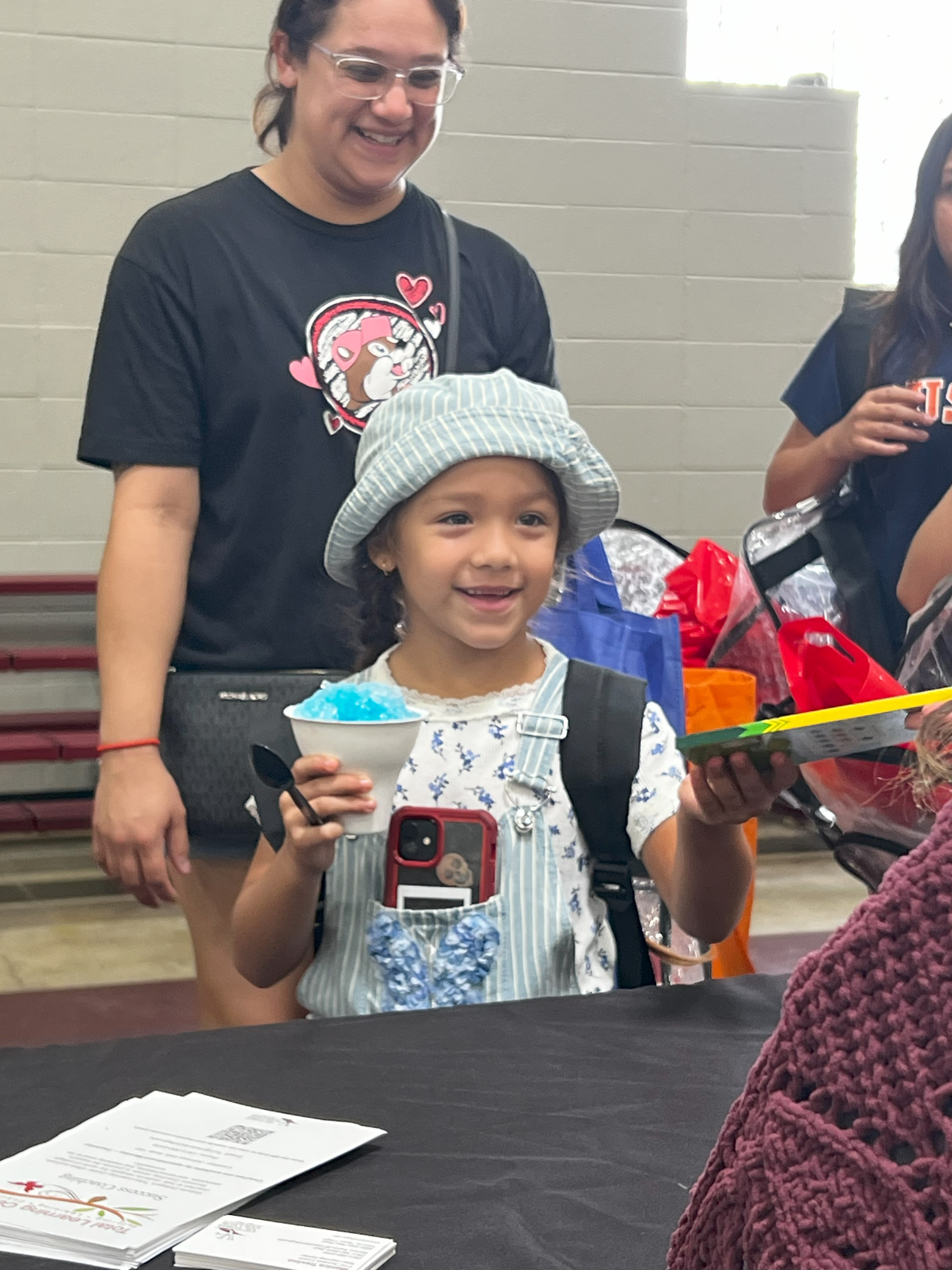 A smiling student holds a snow cone and grabs new colored pencils