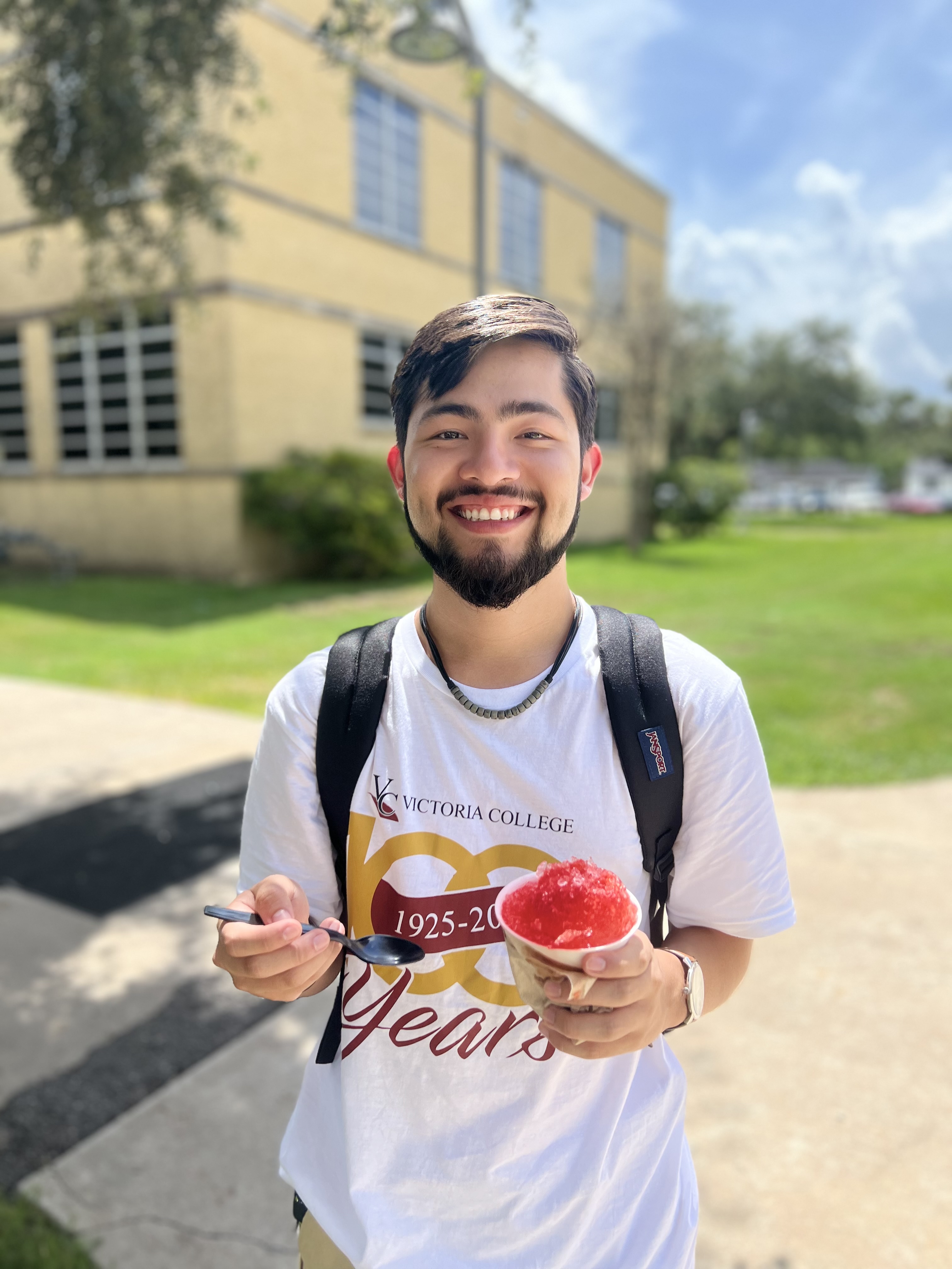 A VC student in a 100th anniversary t-shirt holds a snow cone
