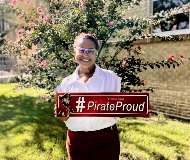 Bridgette smiles holding a Pirate Proud sign