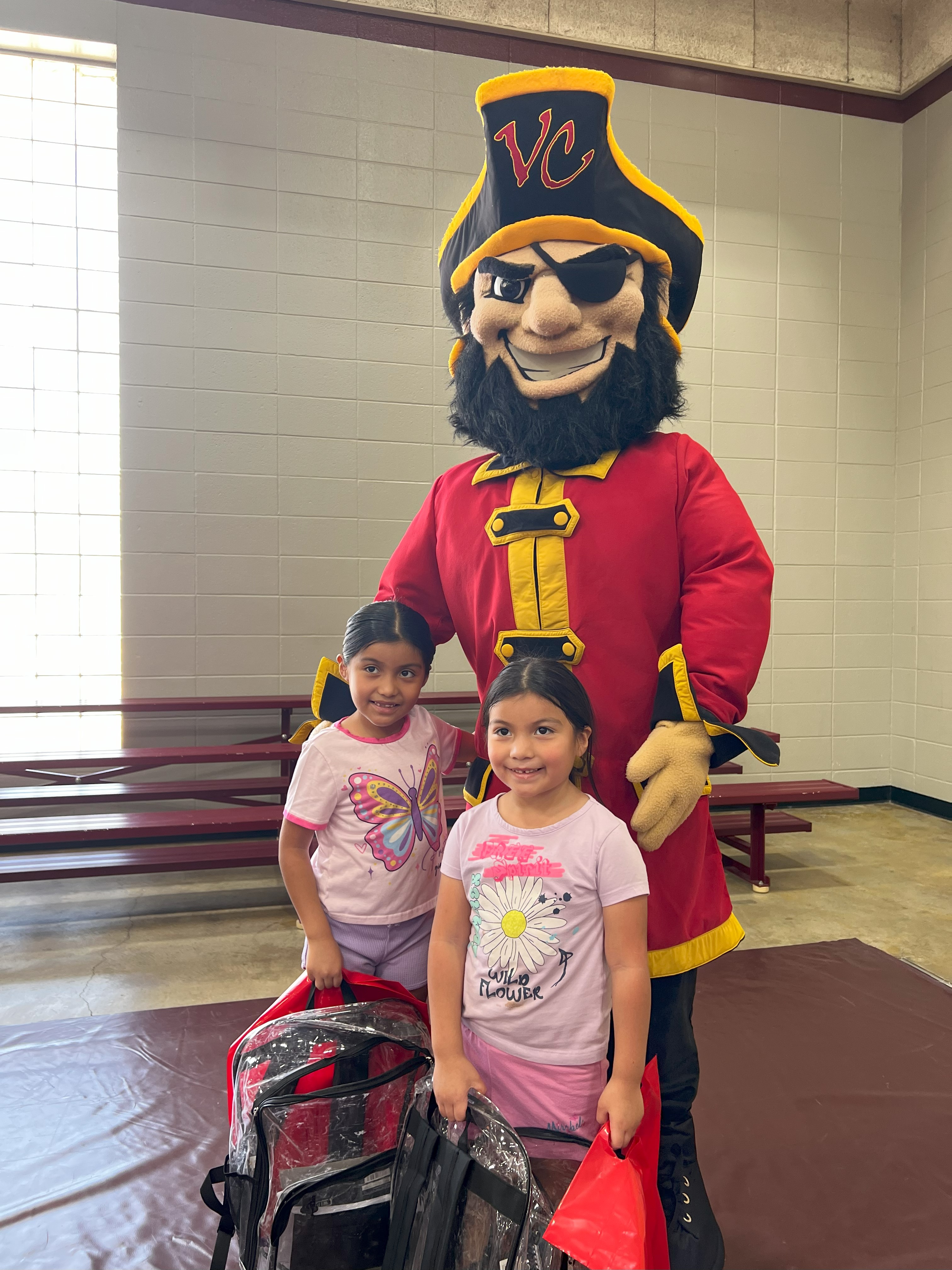 Captain Vic with two young girls holding their backpacks