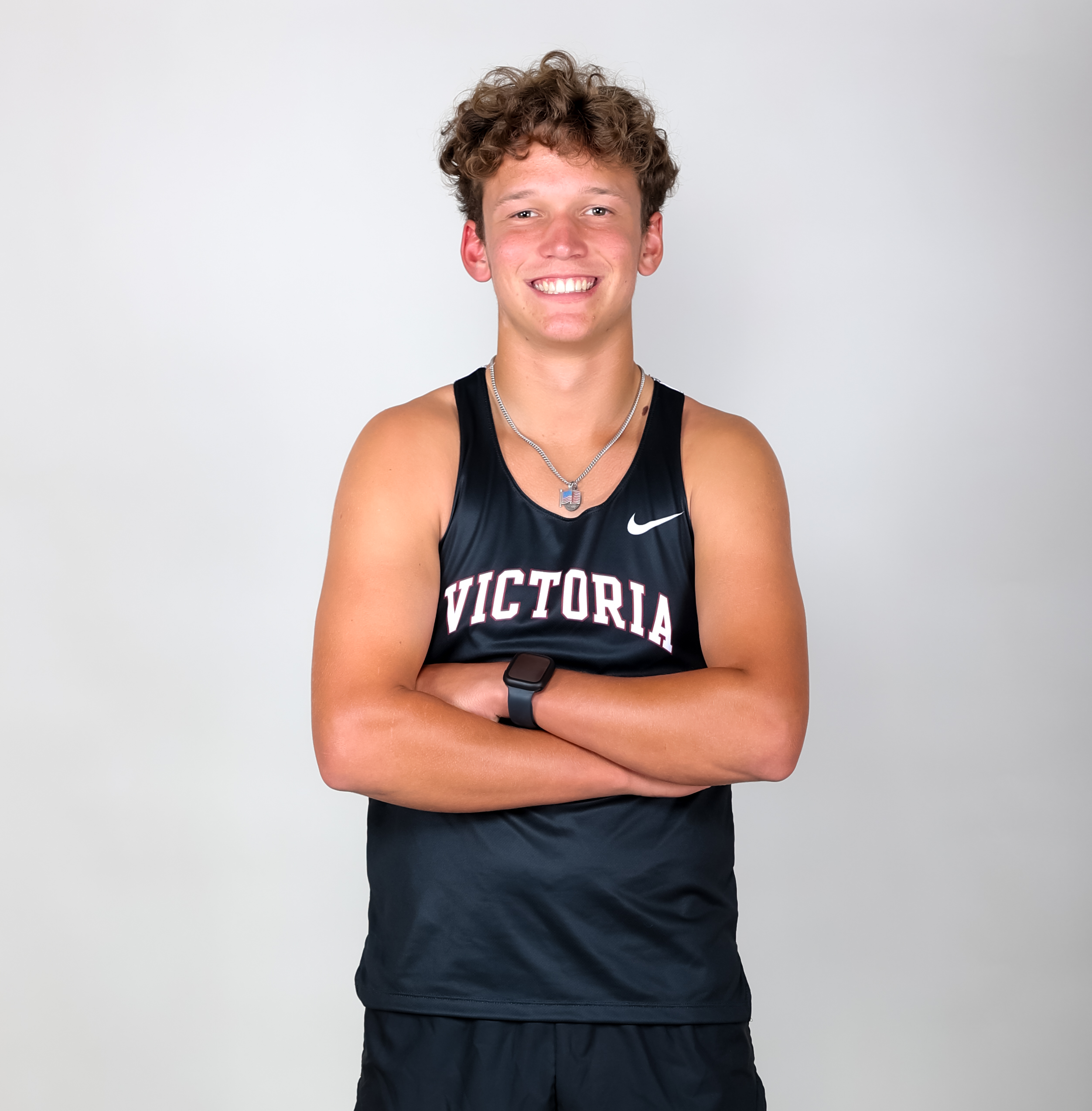 Clayton Hlavac smiling with his arms crossed wearing a black VC uniform