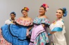 Four smiling folklorico dancers in colorful dresses