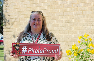 Michelle holds the #PirateProud sign outside on a sunny day