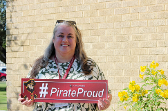 Michelle holds the #PirateProud sign outside on a sunny day