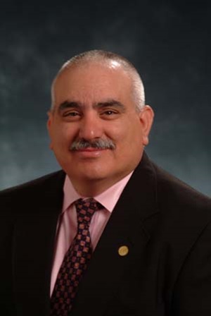 Rene E Ramirez smiles in a suit and tie in a professional headshot