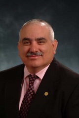 Rene E Ramirez smiles in a suit and tie in a professional headshot