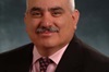 Rene E Ramirez smiles in a suit and tie in a professional headshot