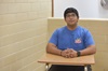 Student David Martinez sits at a desk wearing a blue shirt