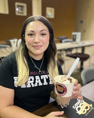 Students in a black Victoria College t-shirt holds an ice cream cup