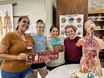 Tutor Alex and 3 nursing students hold a #PirateProud sign in the learning lab