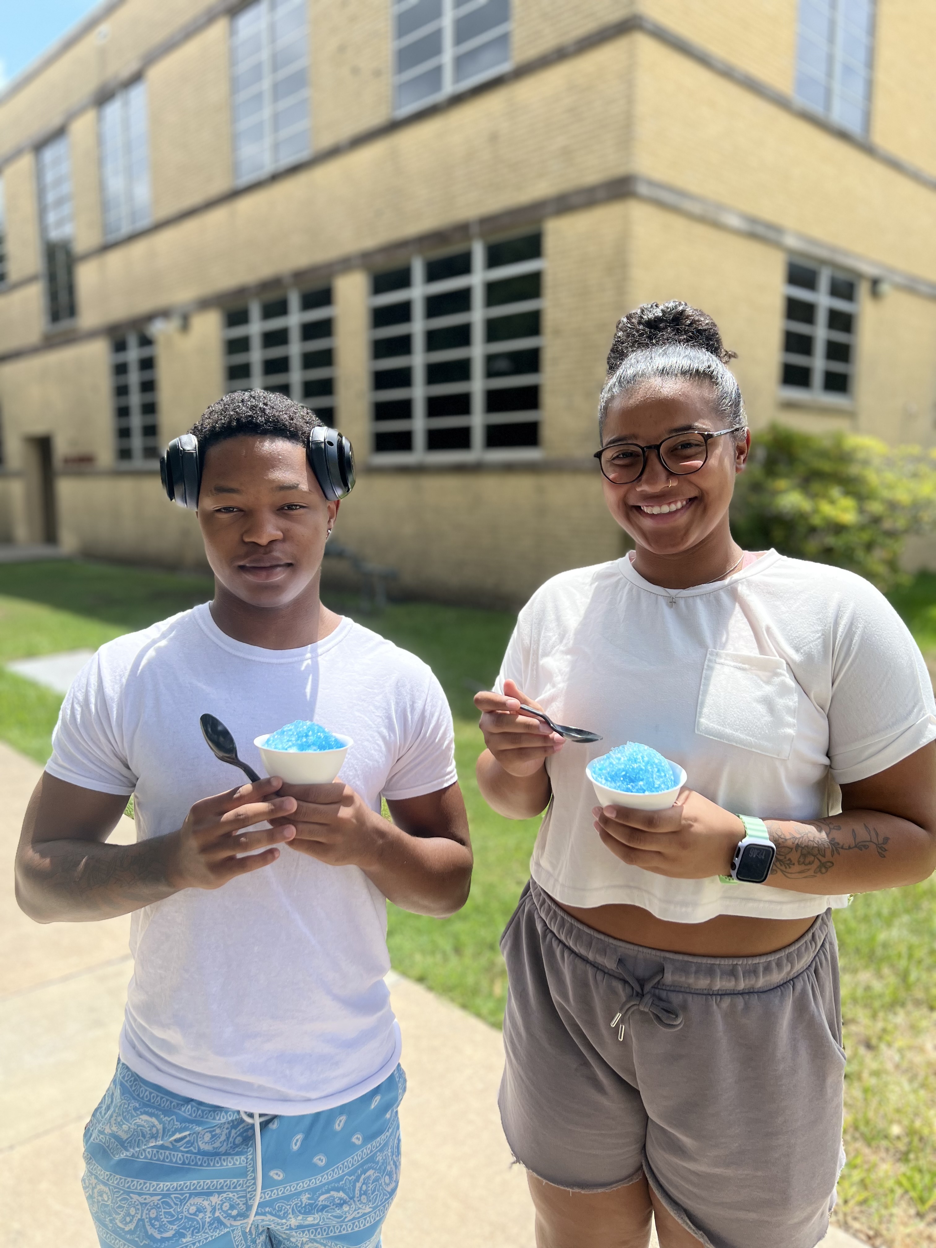 Two VC students hold free snow cones on a sunny day