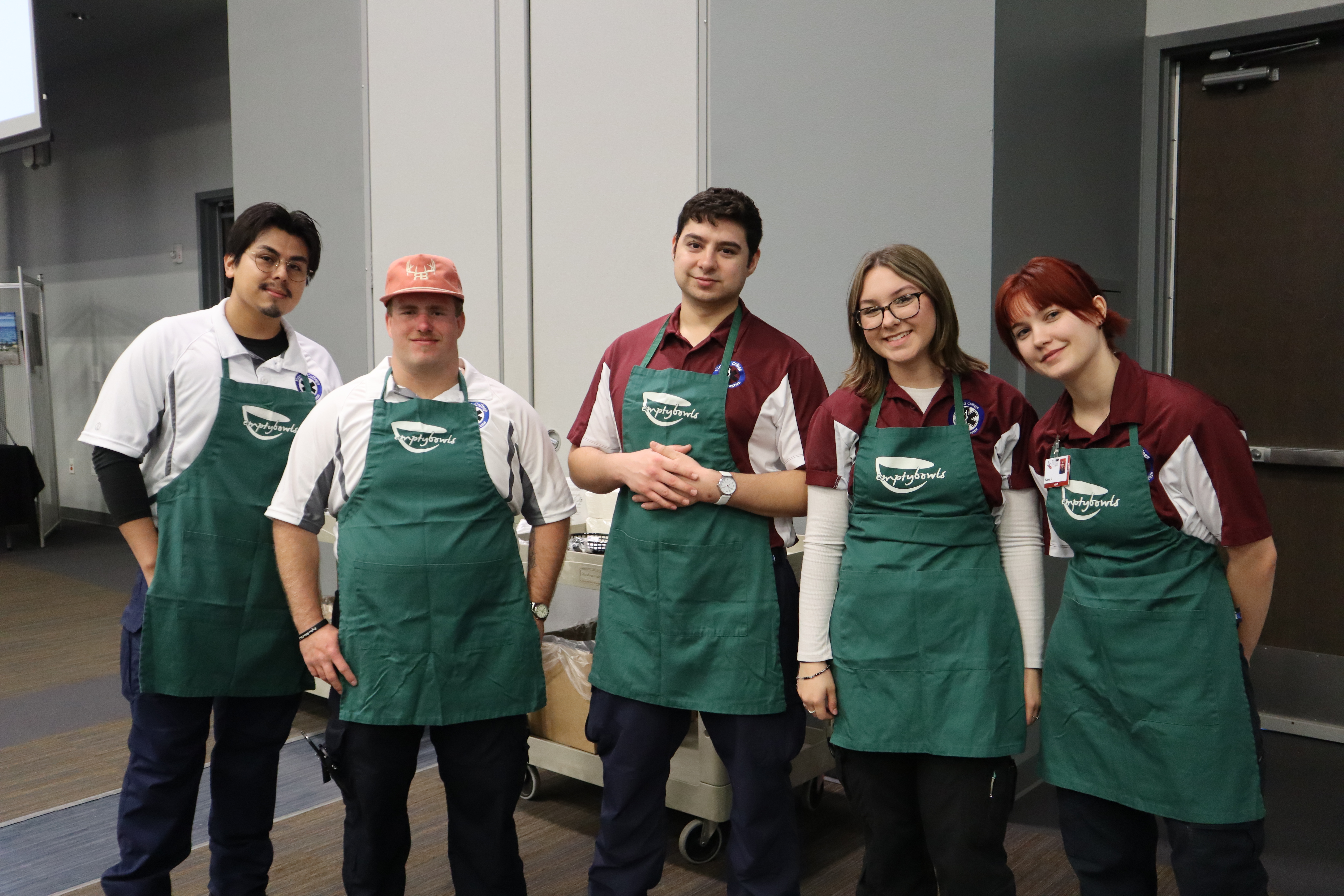 VC students smile wearing green Empty Bowls aprons