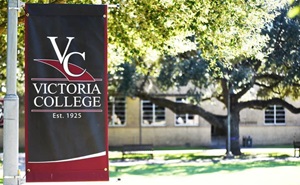 Victoria College maroon and black banner outdoors on a sunny day