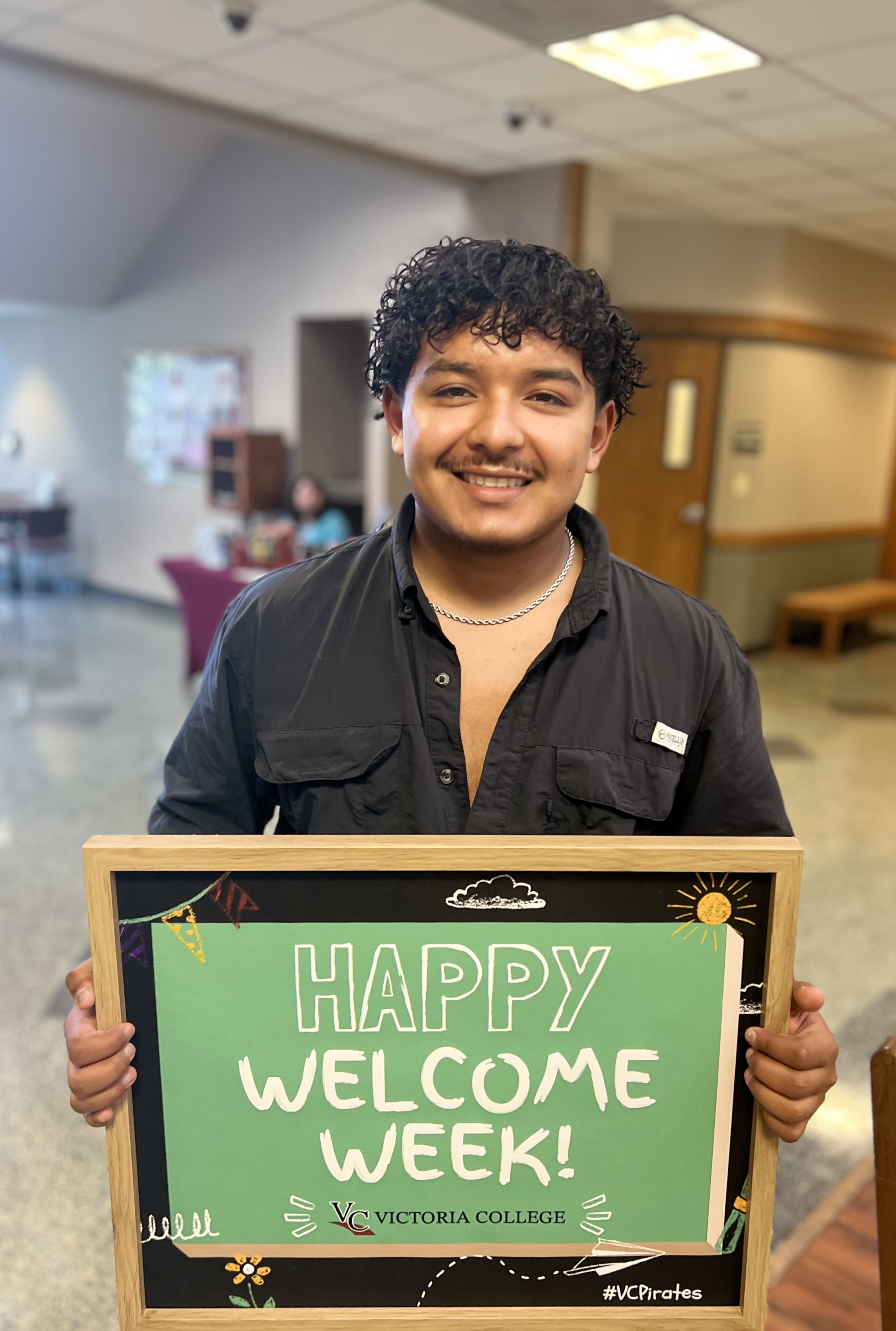 Victoria College students holds up a 'happy welcome week' sign